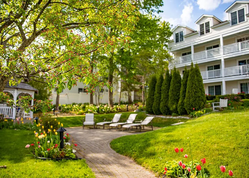 A green garden with brick road in front of a hotel.
