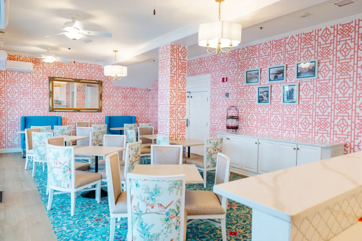 A pink pattern room with blue carpet and blue chairs.